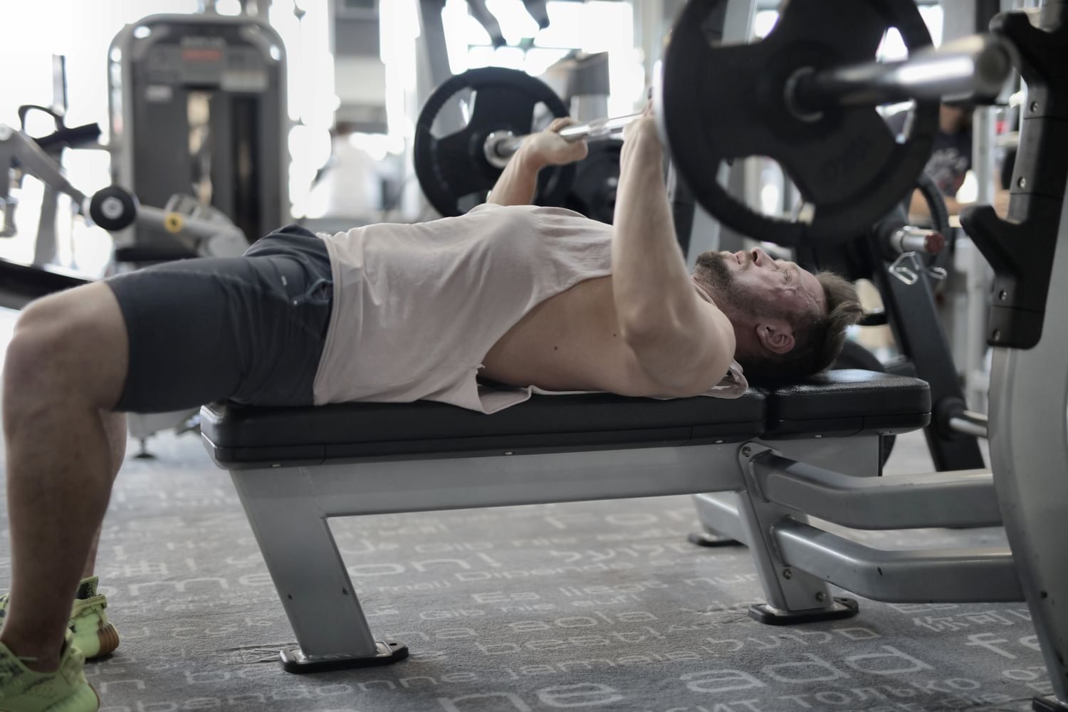 Man performing a barbell bench press in the gym