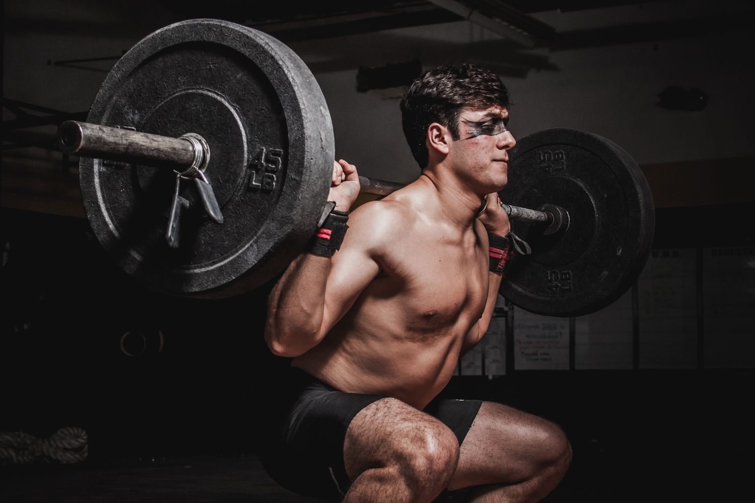 Man performing a heavy barbell back squat during an advanced training session