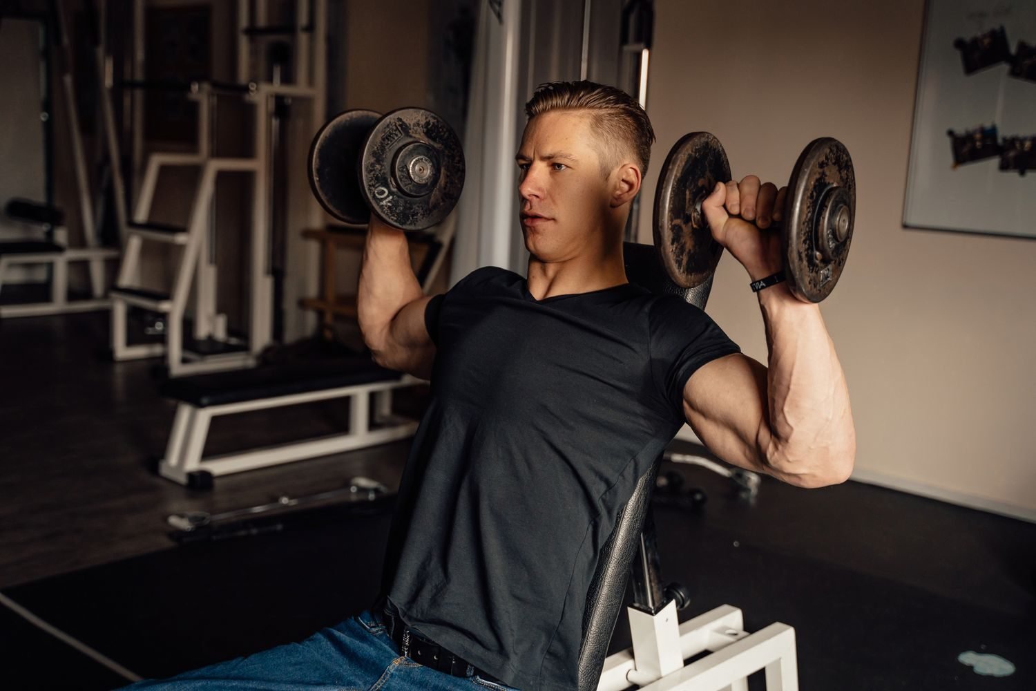 Man performing a seated dumbbell shoulder press at the gym