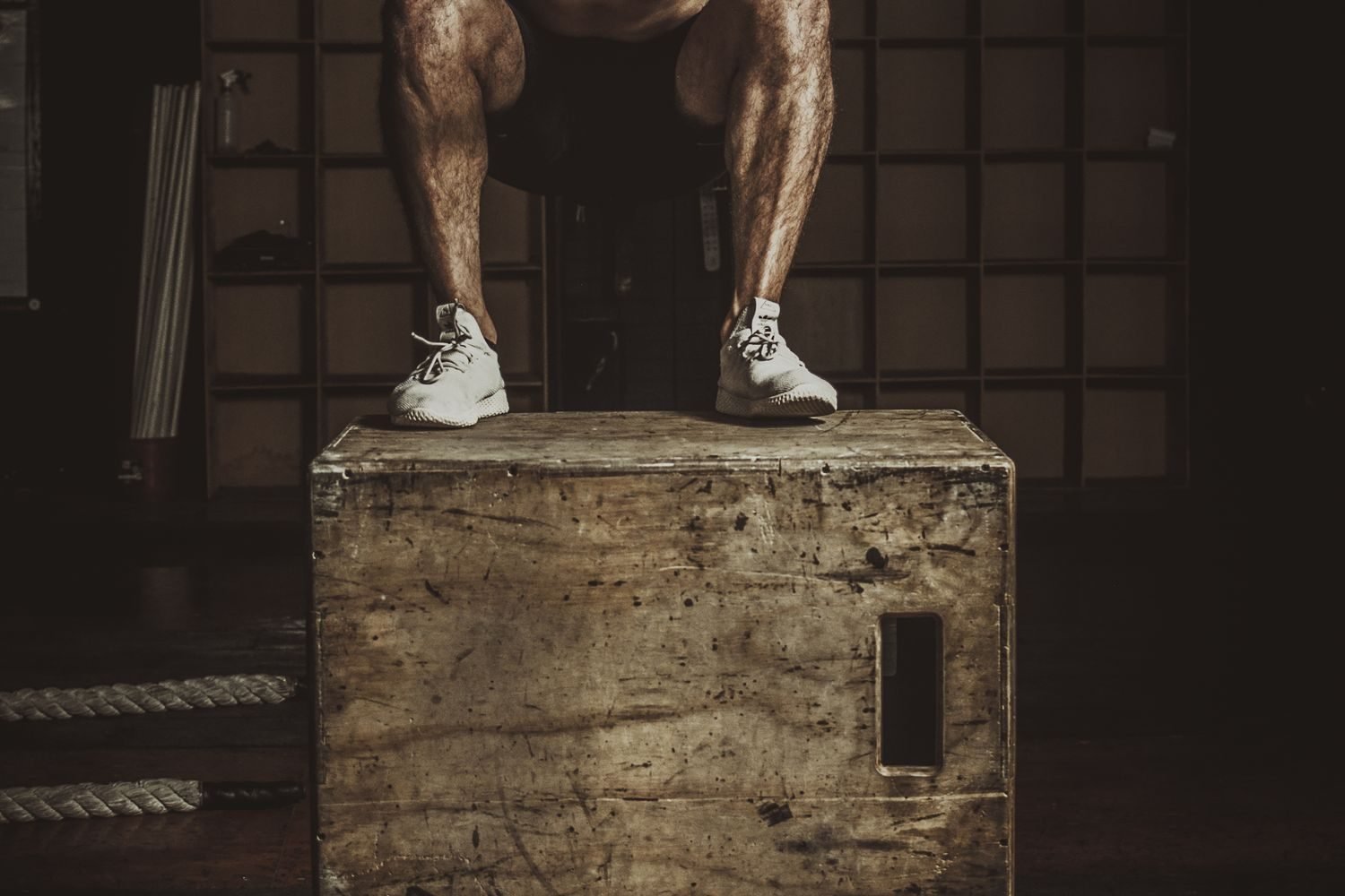 Man performing a box jump exercise in a gym