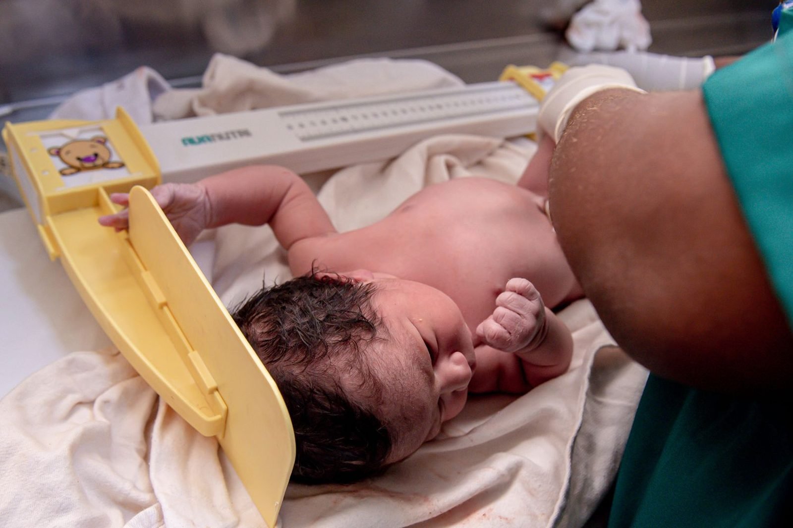 Pediatrician plotting a baby's weight on a WHO growth chart during a well-child checkup
