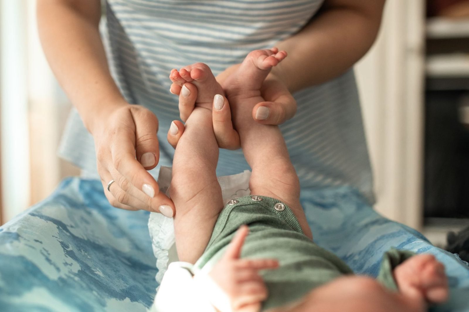 Parent checking a baby's wet diaper as one of the everyday signs of adequate feeding