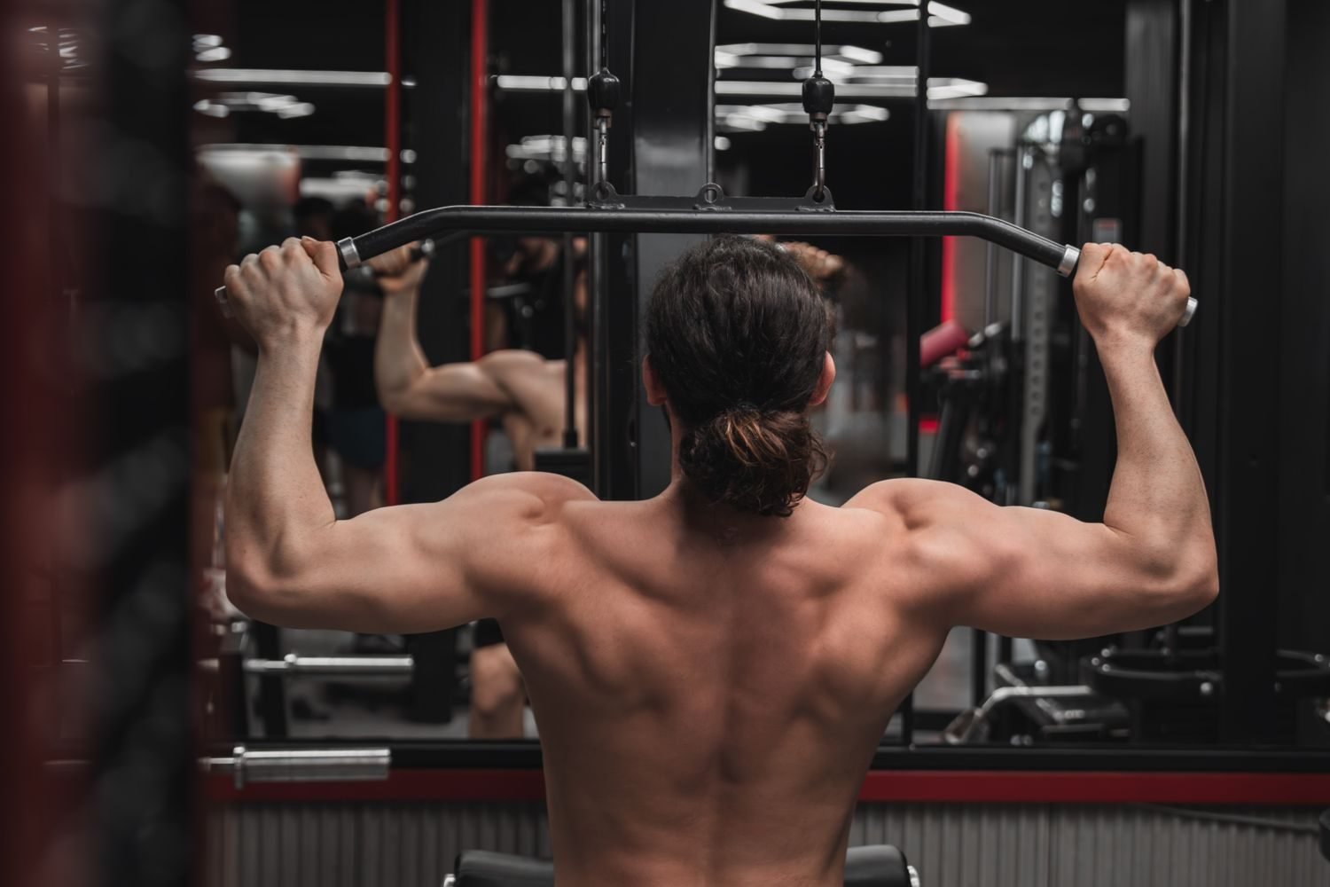 Man performing a lat pulldown exercise, back view showing back muscles