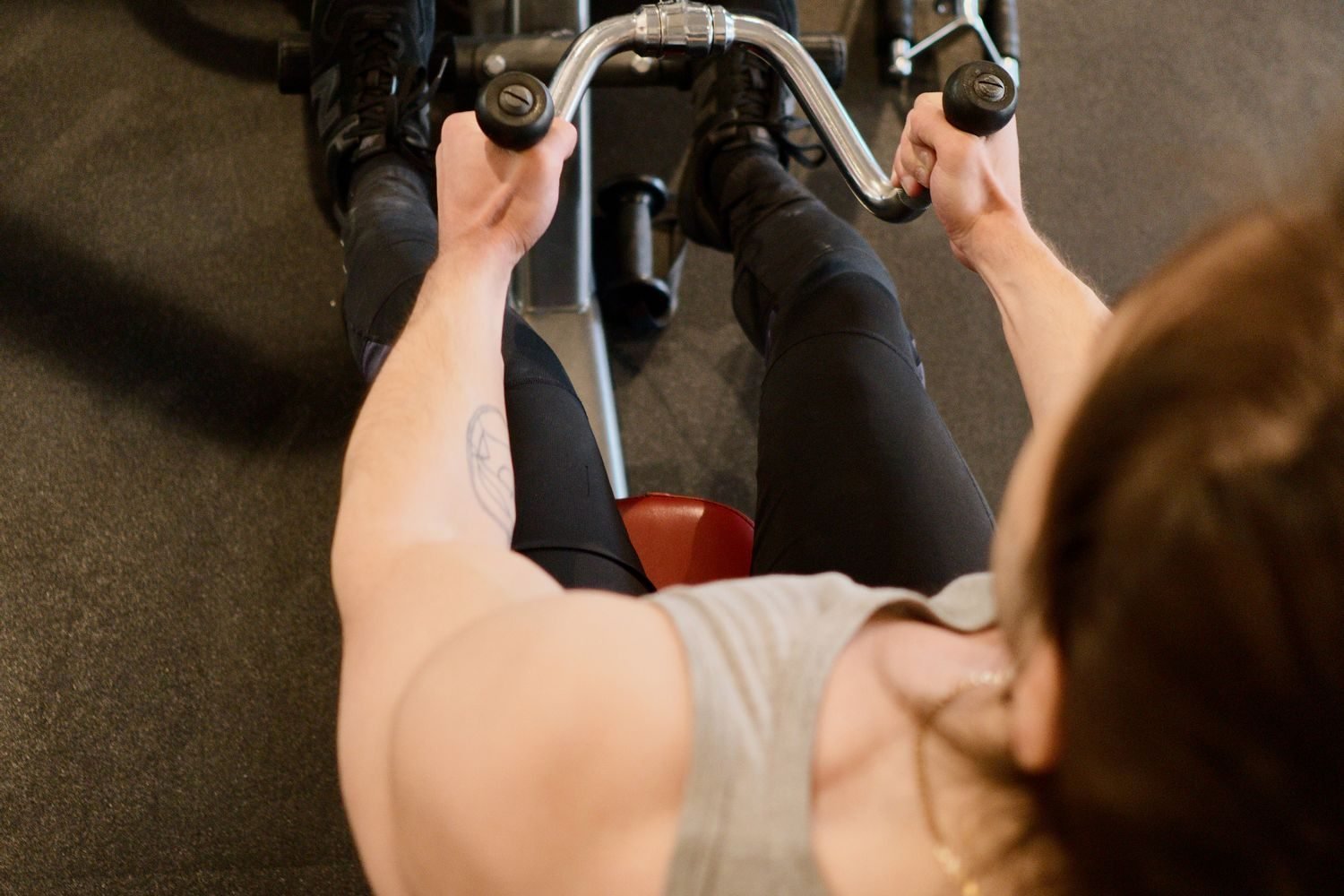 Close-up of a lifter pulling a cable row handle toward the torso with elbows close to the body