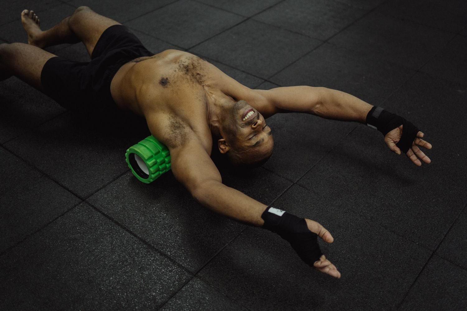 Man foam rolling his upper back on the gym floor