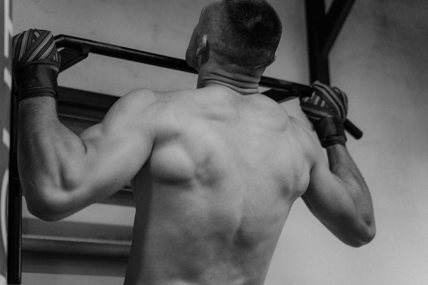 Man performing a pull-up on a bar, showing back muscle engagement
