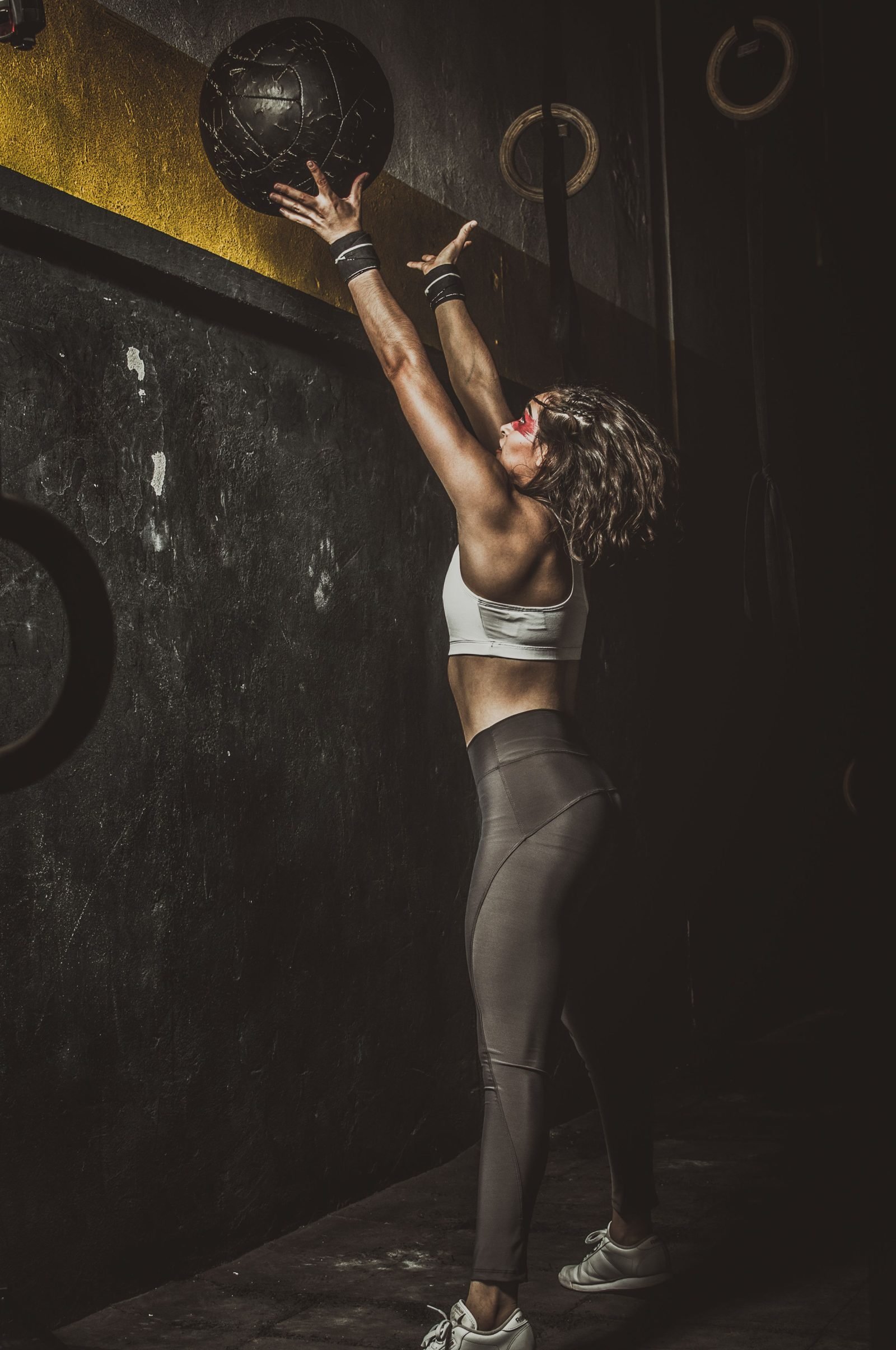 Woman throwing a slam ball overhead during training