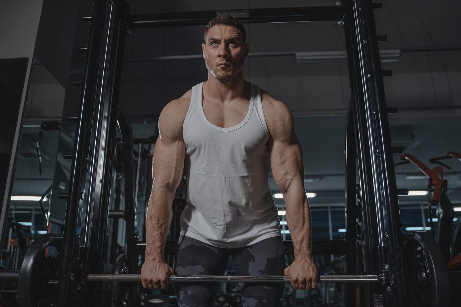 Lifter standing tall holding a barbell at hip level in a gym rack