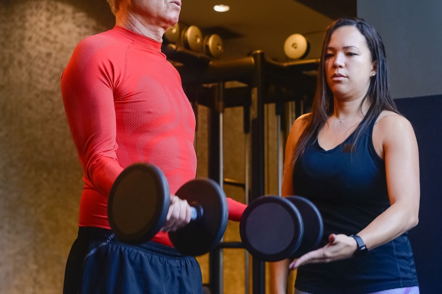 Personal trainer coaching a client through a dumbbell exercise