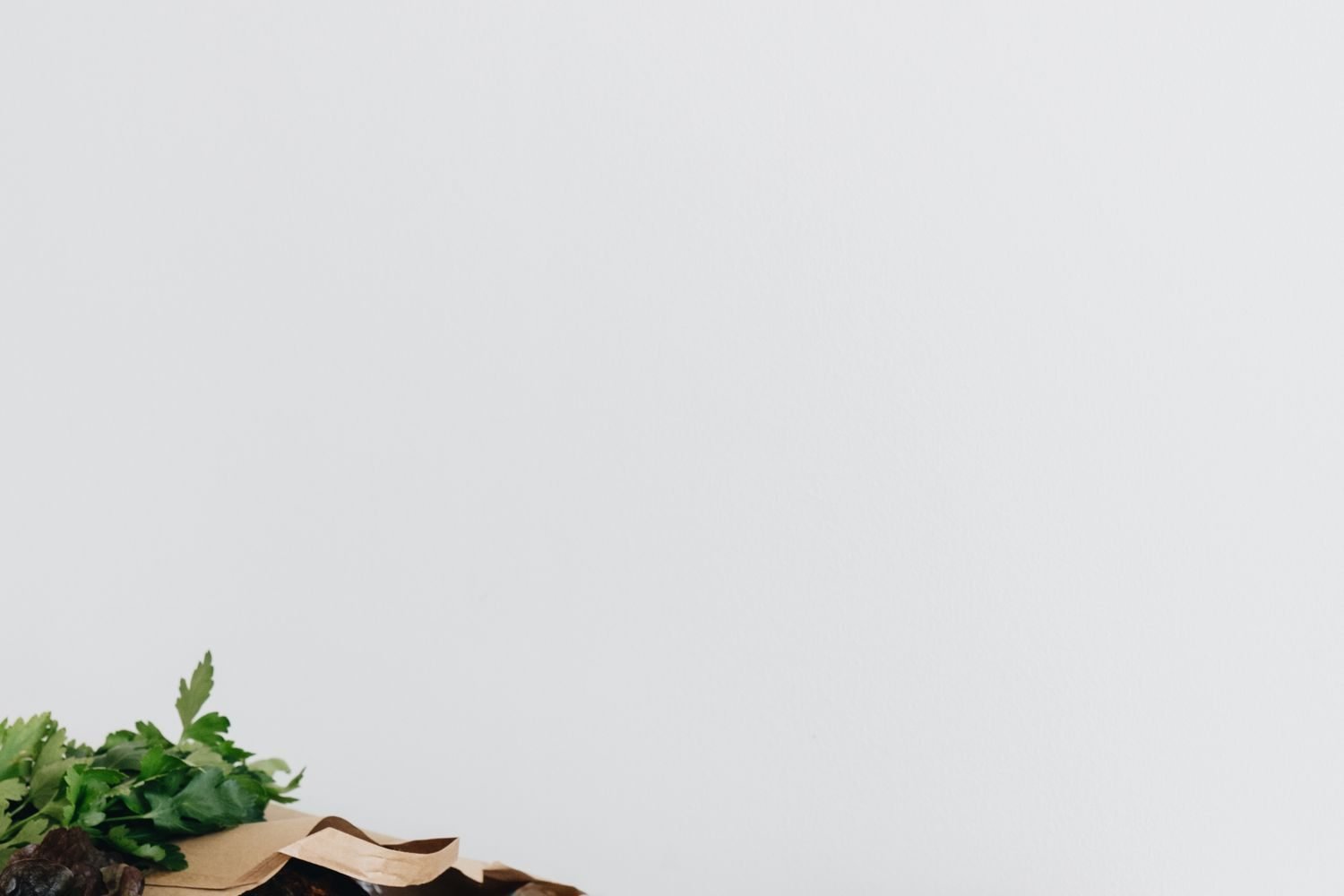 Person planning a heart-healthy grocery list with fresh produce, fish, and whole grains on a kitchen counter