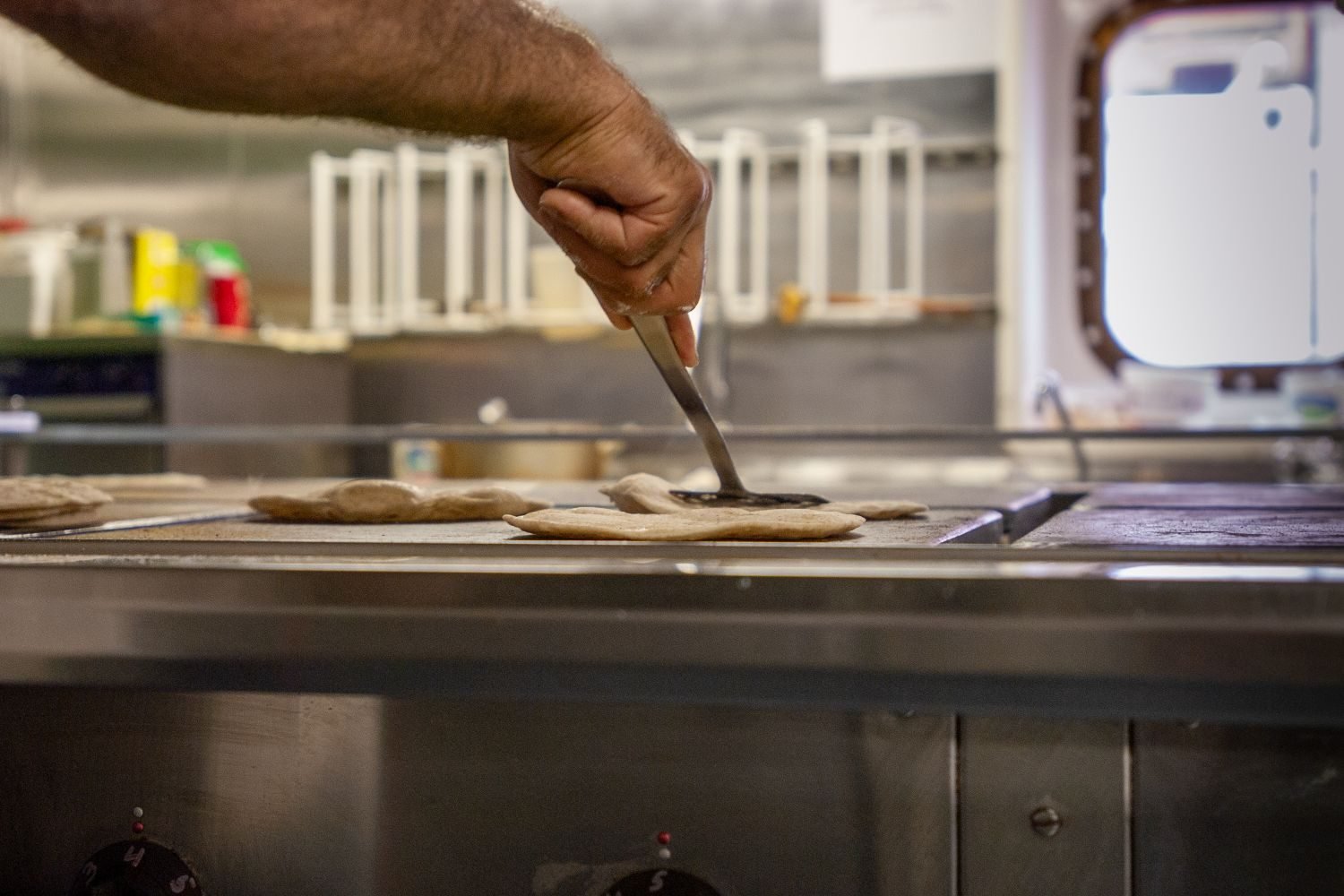 Hand rolling jowar flour dough into a flatbread on a wooden board