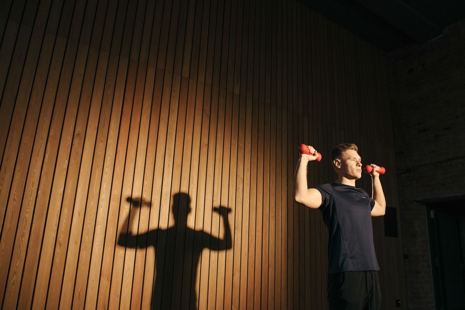 Man lifting dumbbells in warm evening light
