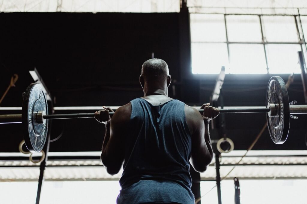 Man viewed from behind lifting a loaded barbell during a gym weightlifting session