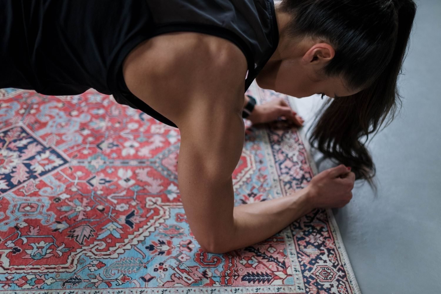 Woman performing a bodyweight plank exercise at home on a rug