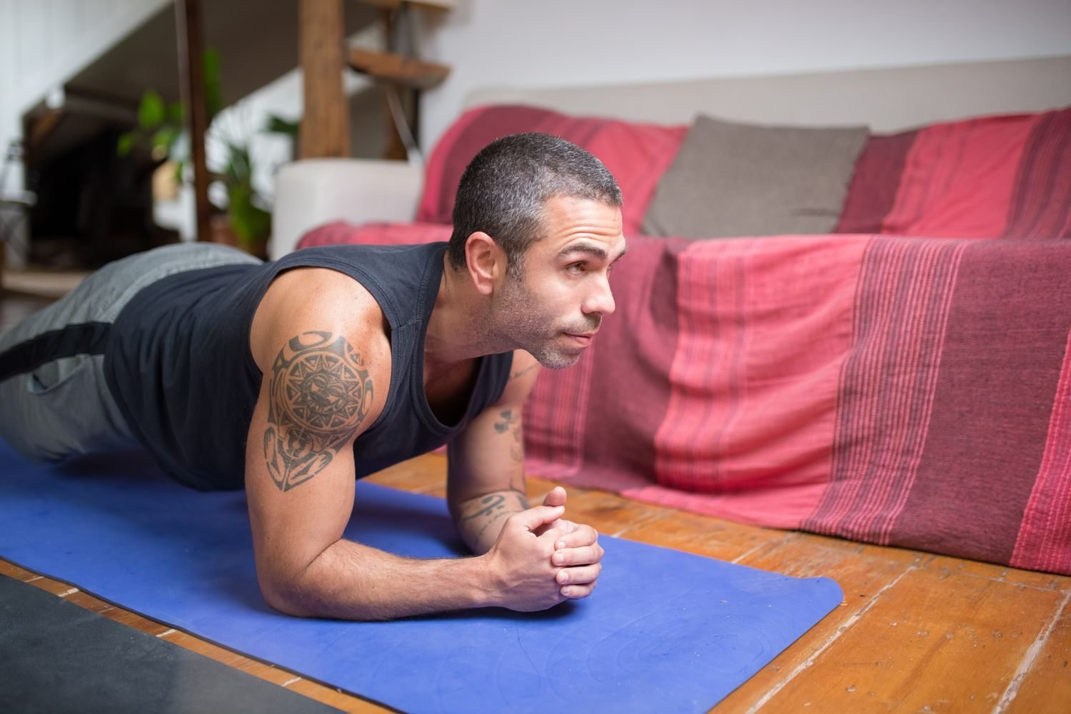 Man holding a forearm plank on a mat at home