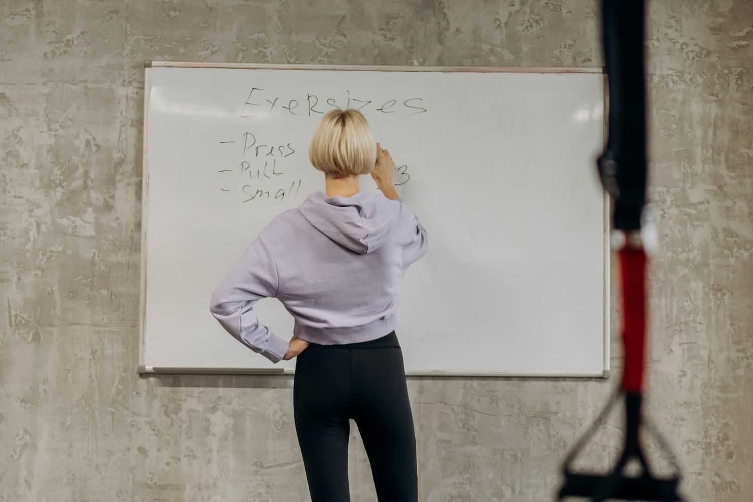 Person writing a workout plan on a whiteboard