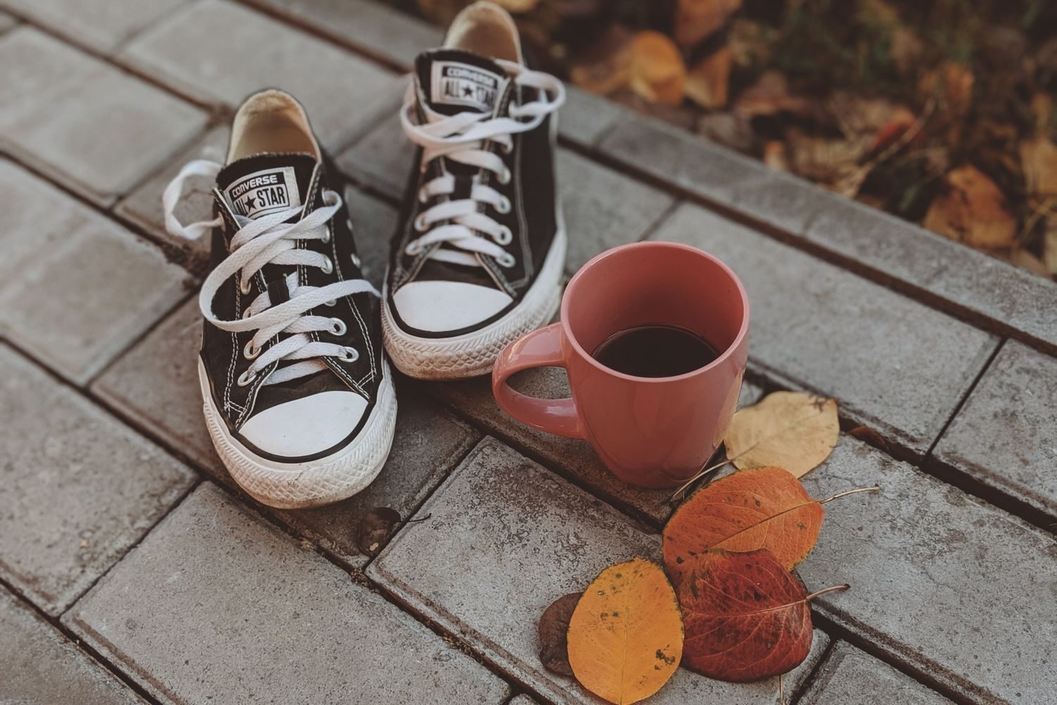 Cup of coffee next to a stopwatch and running shoes representing caffeine timing before exercise