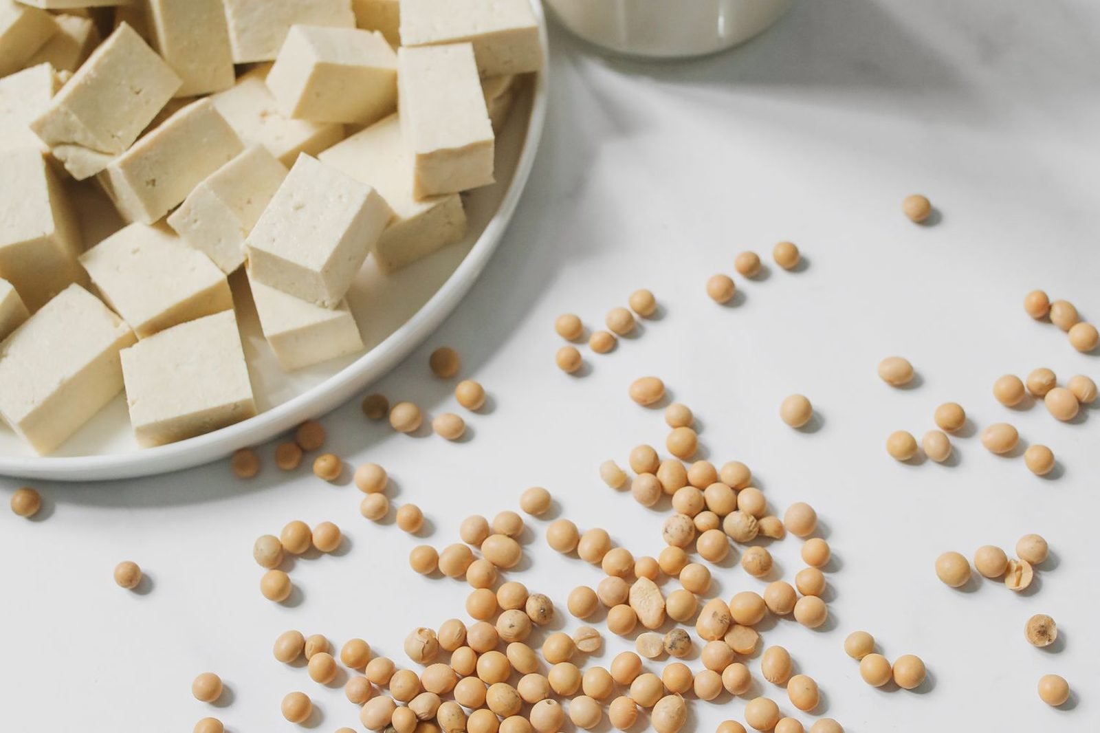 Comparison chart-style flat lay of non-dairy calcium sources: tofu, fortified soy milk, sardines, kale, and chia seeds