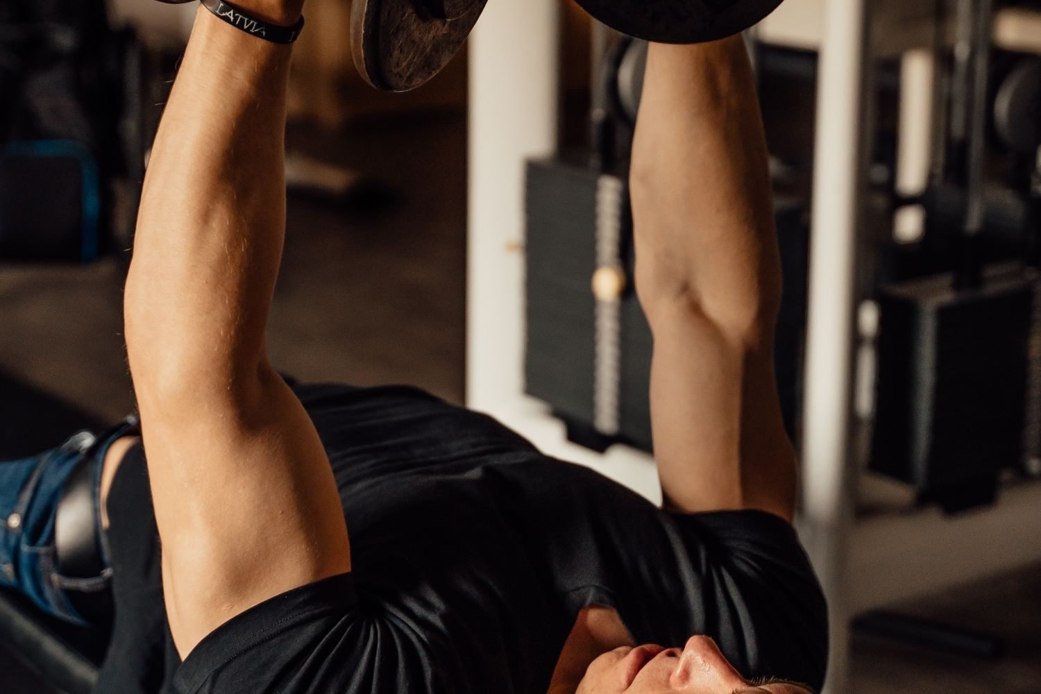 Man performing a dumbbell bench press at the gym