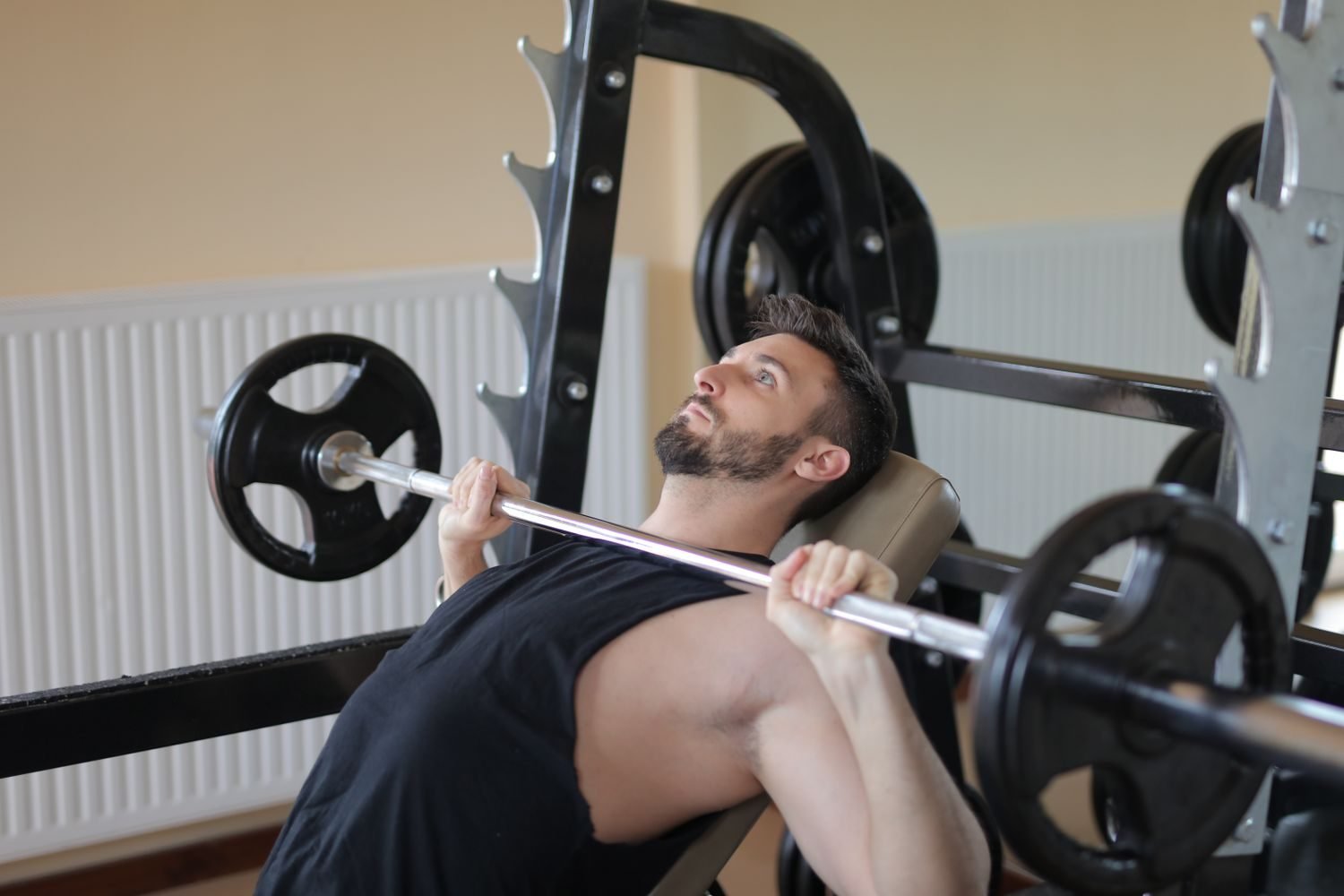 Man performing a flat barbell bench press in a home gym