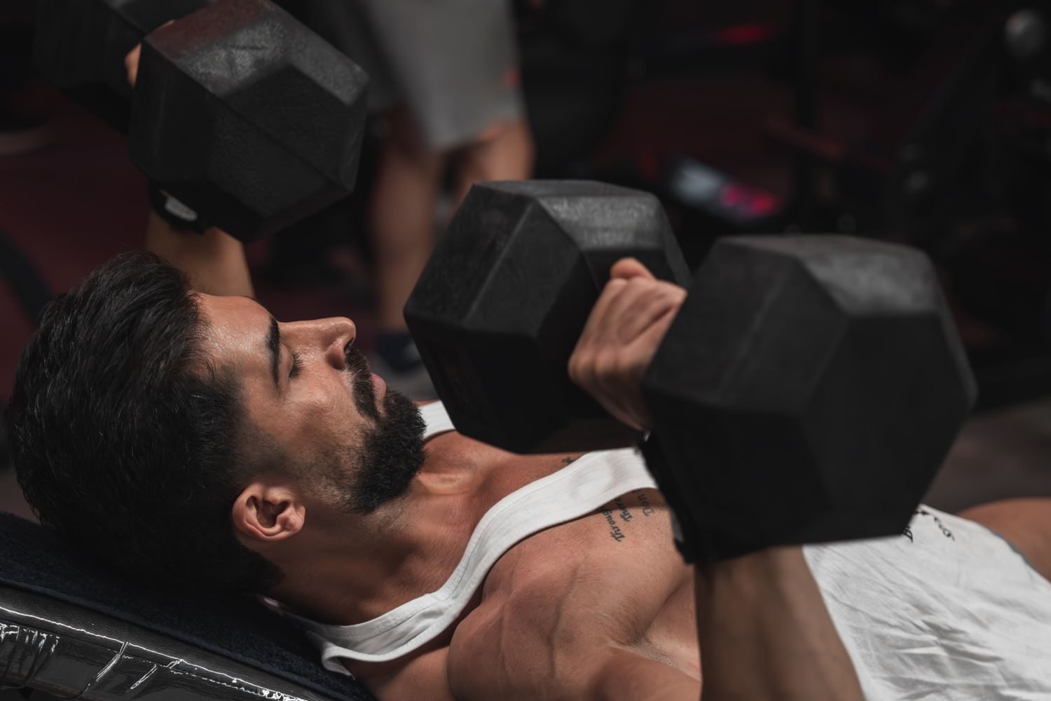 Man performing an incline dumbbell press with both arms extended overhead
