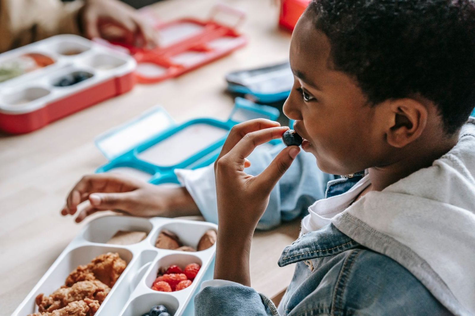 Child eating a balanced breakfast with eggs, whole grain toast, and fruit before school