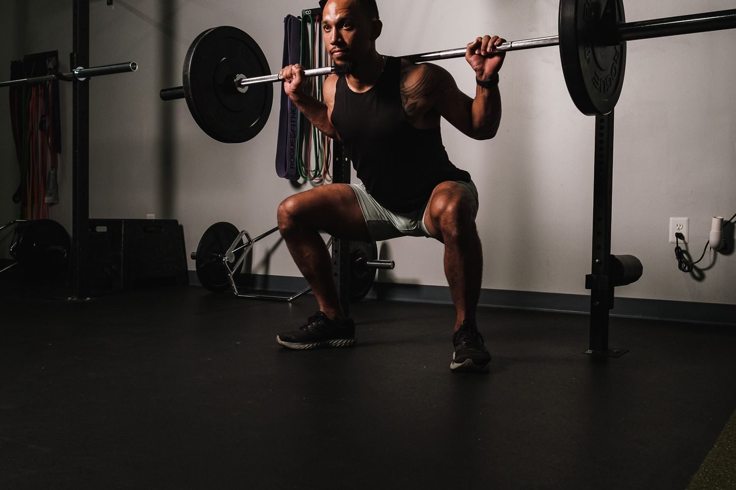 Woman performing a barbell back squat with a squat rack