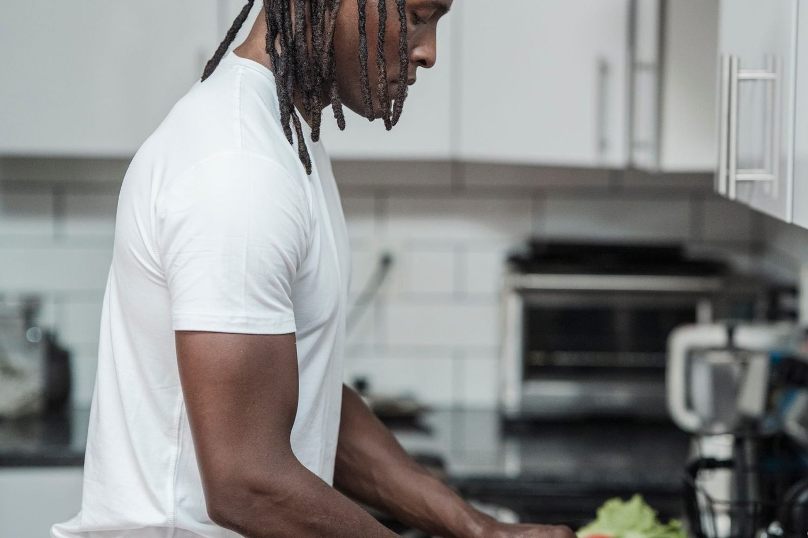 Active man preparing a post-workout meal with vegetables and protein in a home kitchen