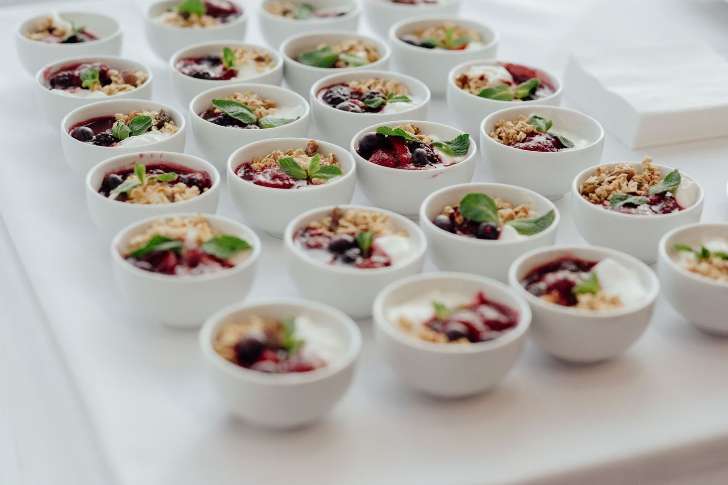 Small glass bowls of roasted chana, mixed nuts, and Greek yogurt with berries arranged as portioned diabetes-friendly snacks