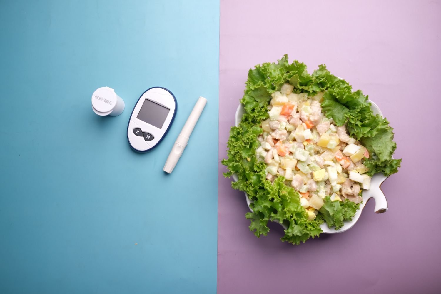 Person checking blood glucose monitor next to a plate of vegetable sticks, hummus, and boiled eggs on a kitchen counter