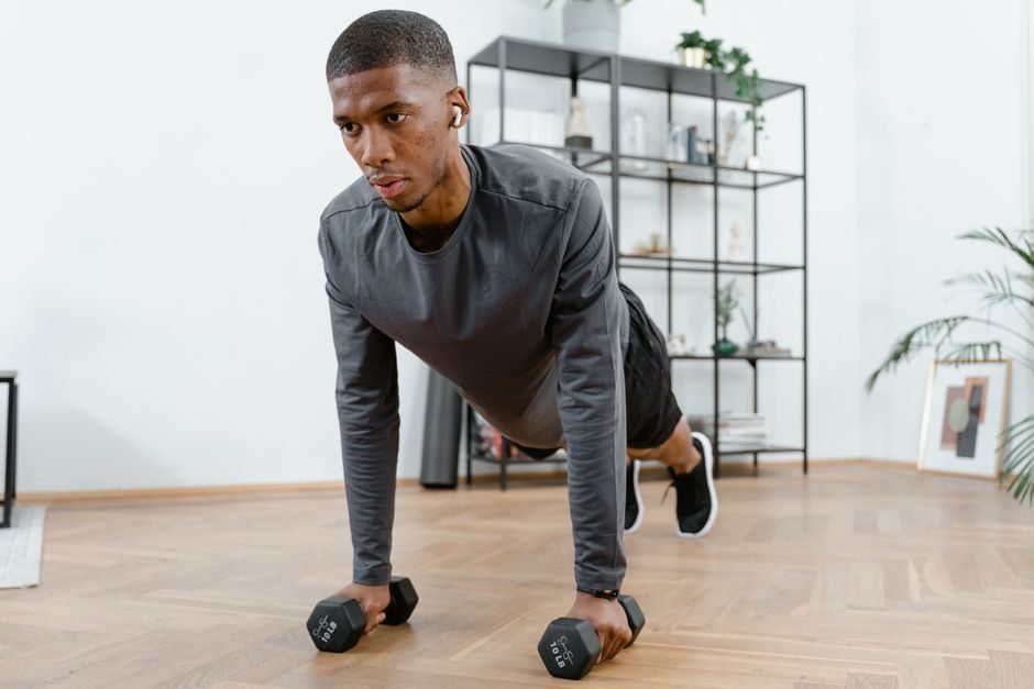 Man holding a plank position with dumbbells during a full body HIIT workout at home