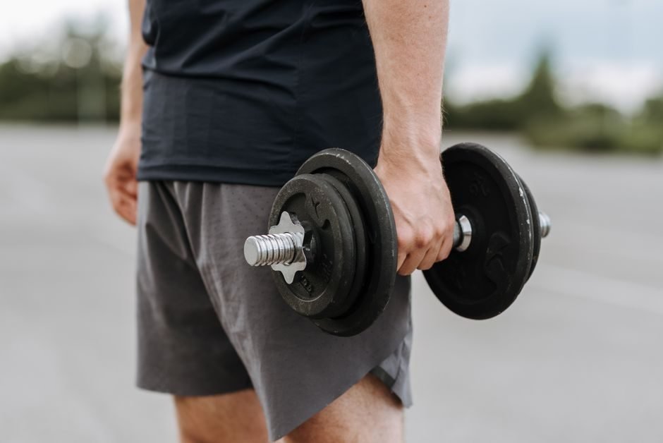Man carrying a dumbbell at his side during a farmer's carry exercise