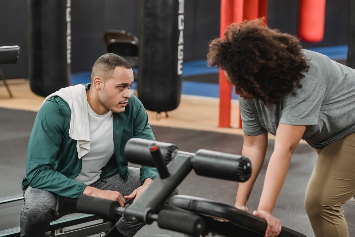 Trainer guiding a beginner through gym equipment