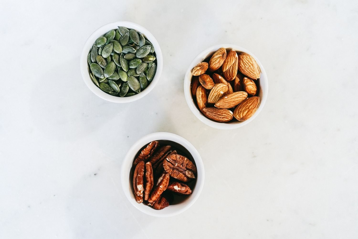 Close-up of raw almonds and pumpkin seeds in a small bowl, both rich in magnesium and tryptophan