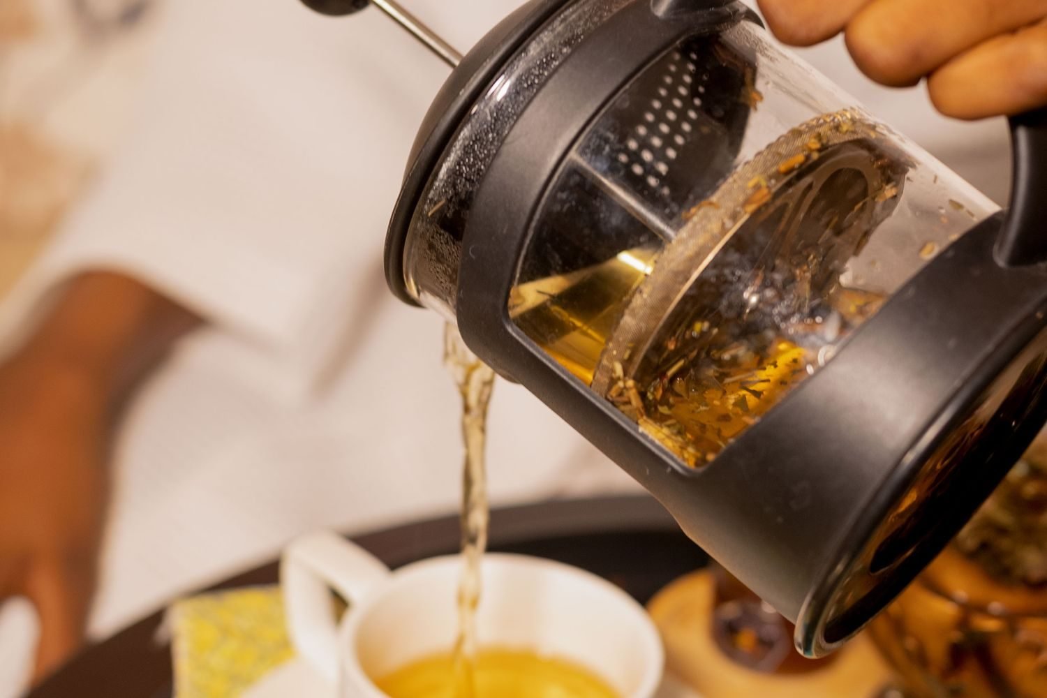 Person setting aside a cup of coffee and glass of wine in the evening, choosing herbal tea instead to protect sleep quality