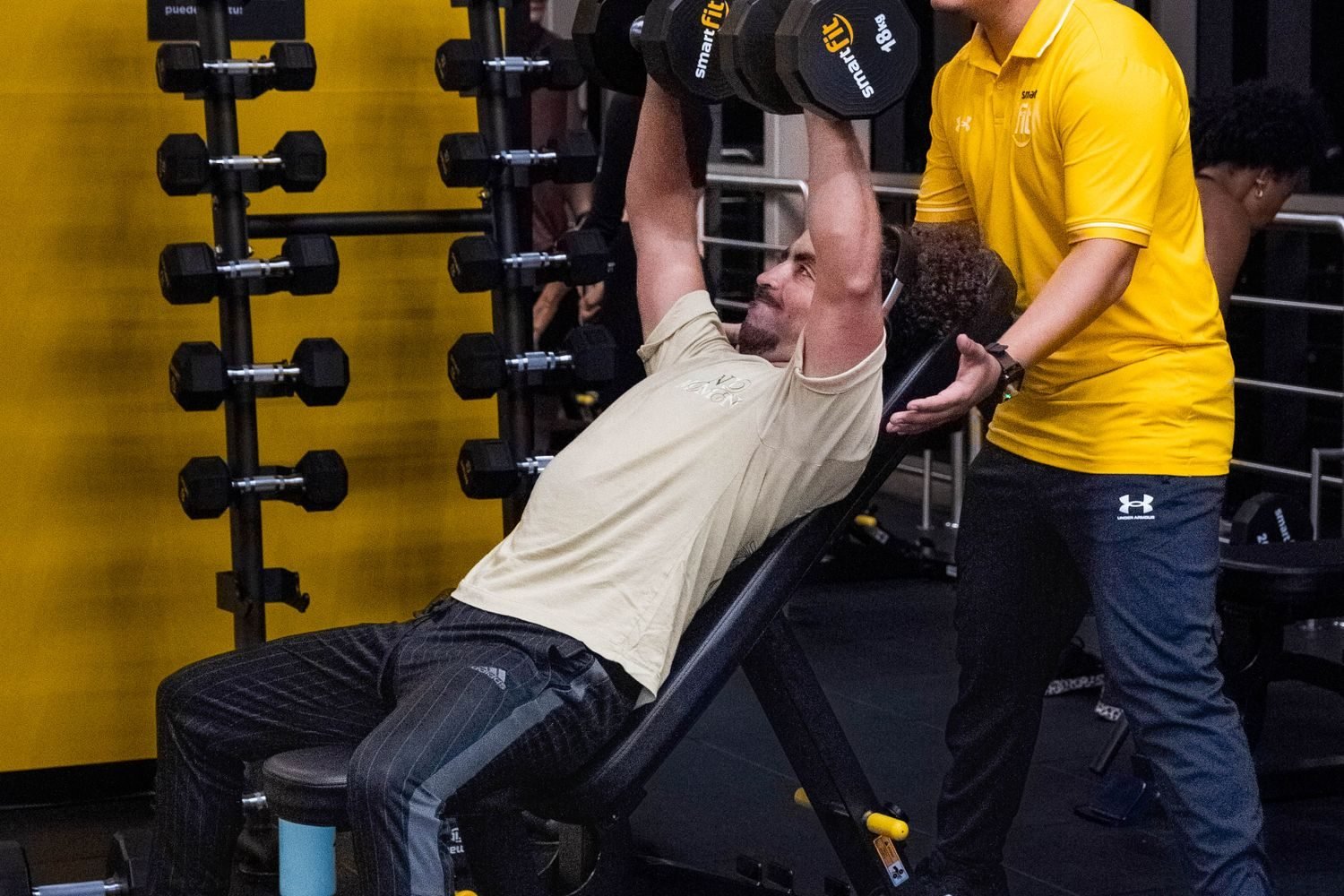 Personal trainer spotting a client during an incline dumbbell press