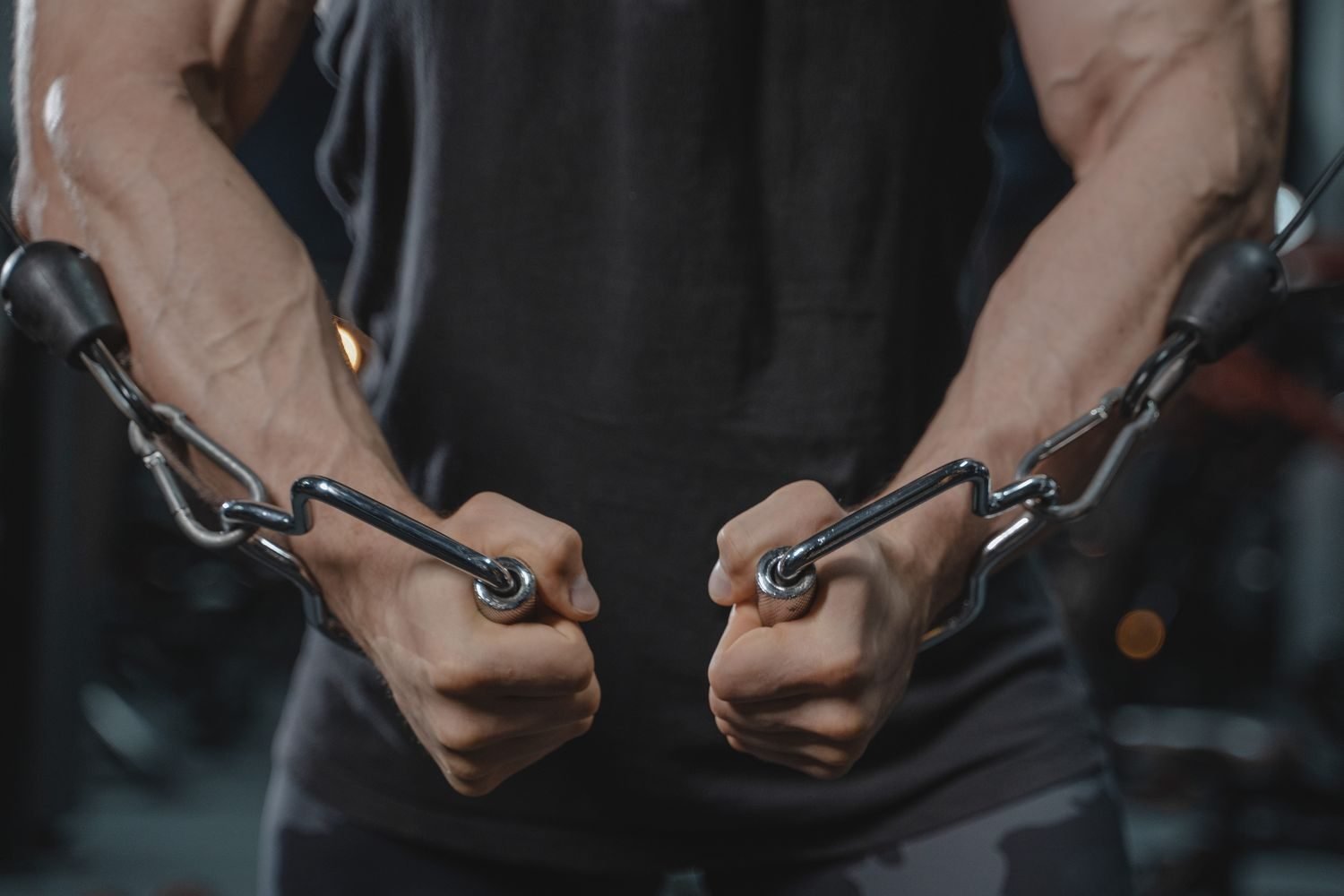 Man gripping cable handles for a shoulder cable exercise