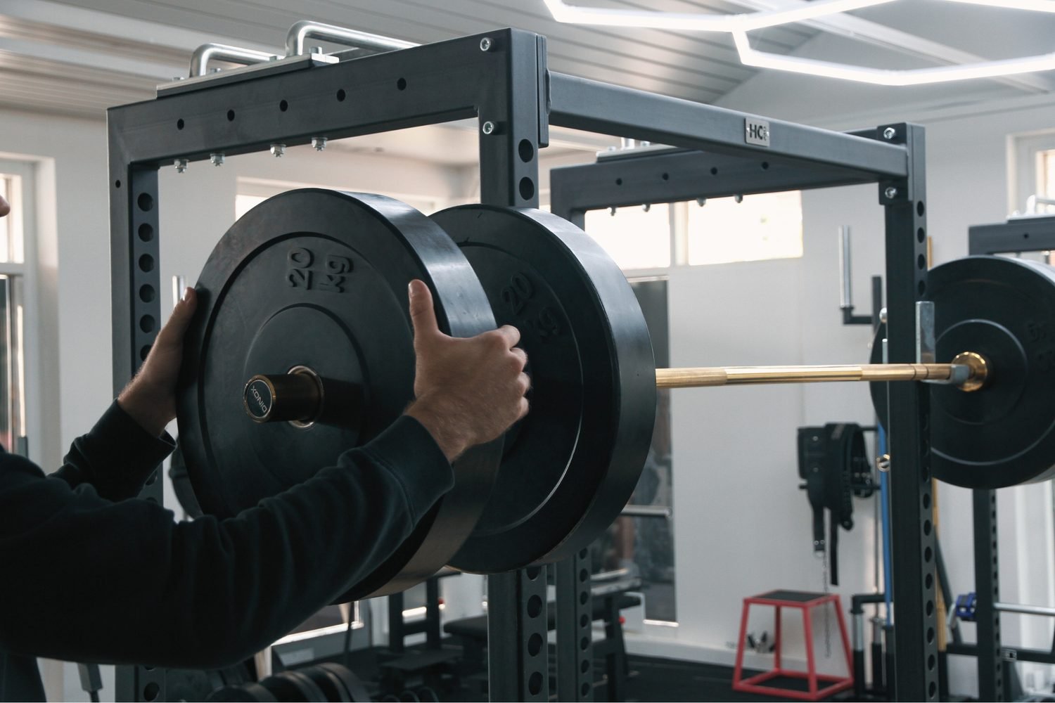Man loading weight plates onto a barbell in a squat rack