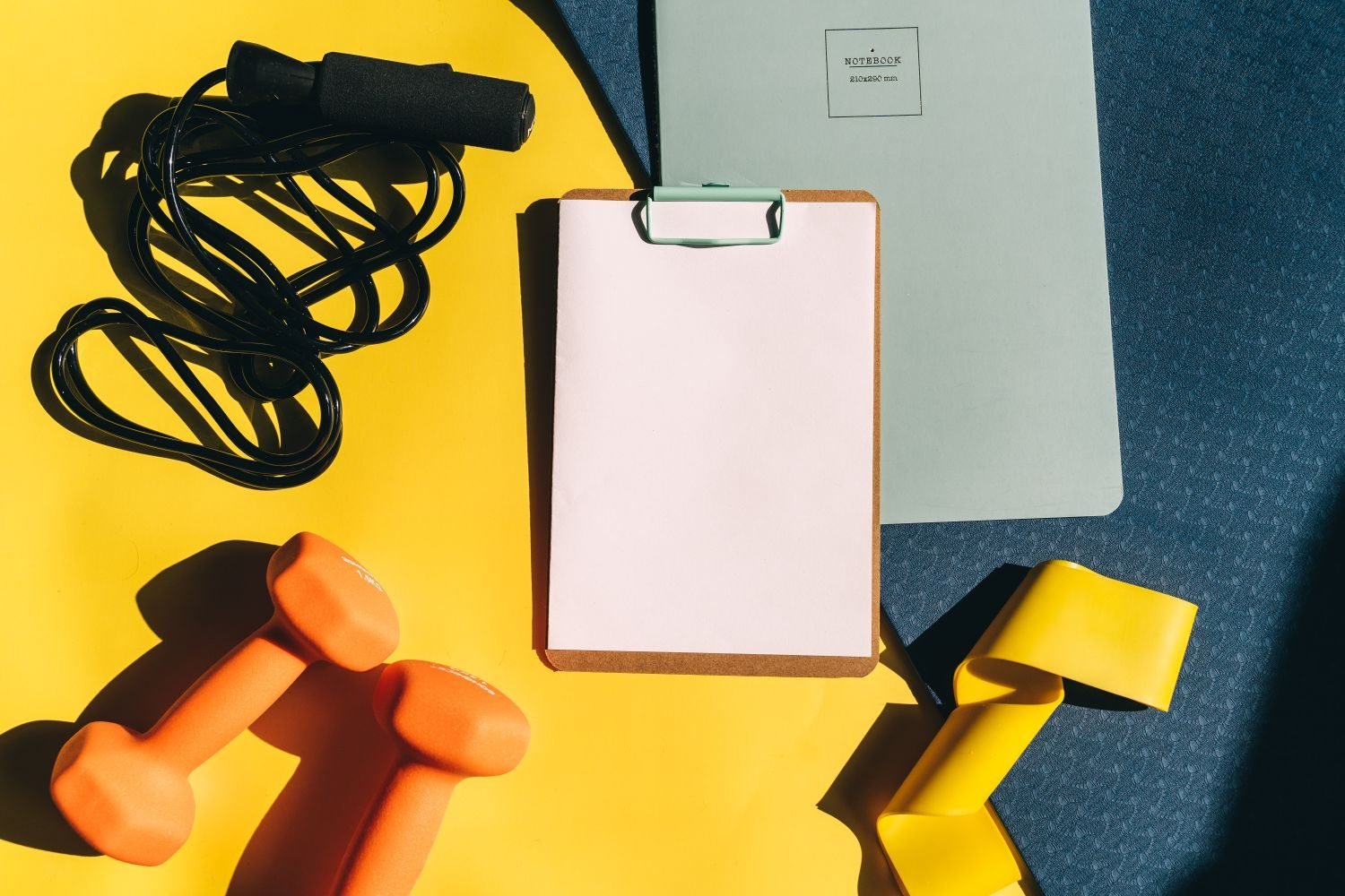 Notebook and gym equipment flat lay for planning a weekly workout