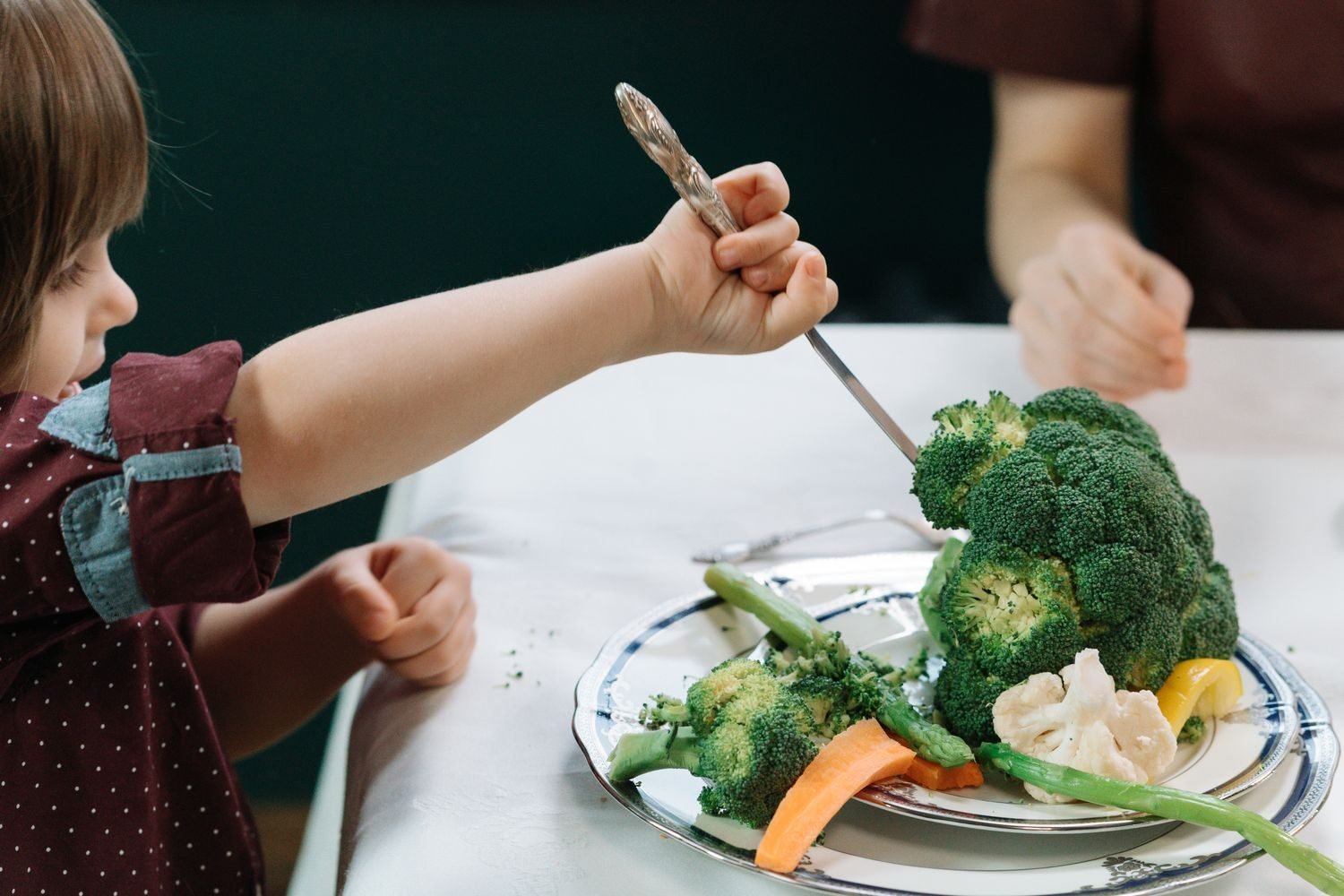 Person adding a serving of vegetables to their plate at home as a small daily habit