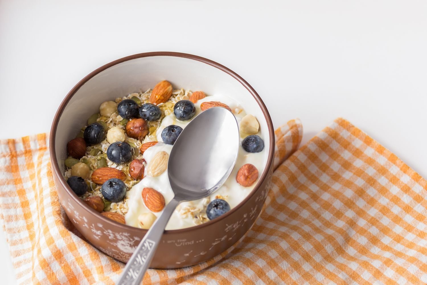 Small bowls of high-protein high-fiber snacks including Greek yogurt, almonds, and berries arranged on a kitchen counter