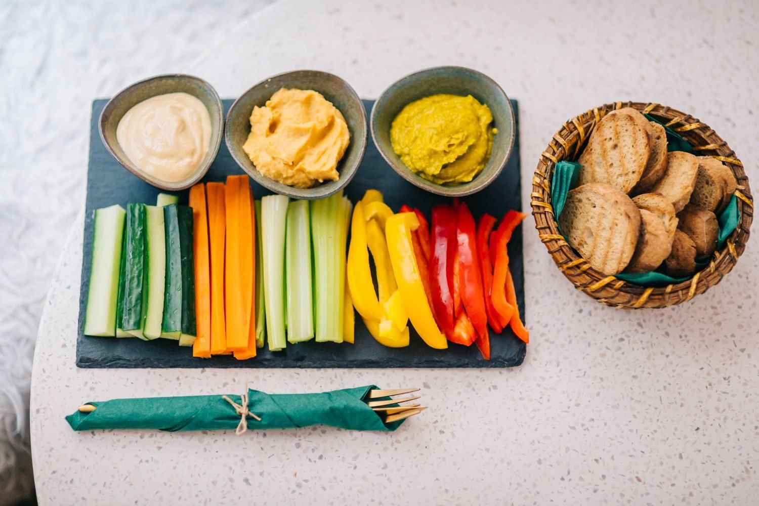Comparison of a low energy-dense snack plate with cucumber, carrots, and hummus next to a small portion of high energy-dense trail mix