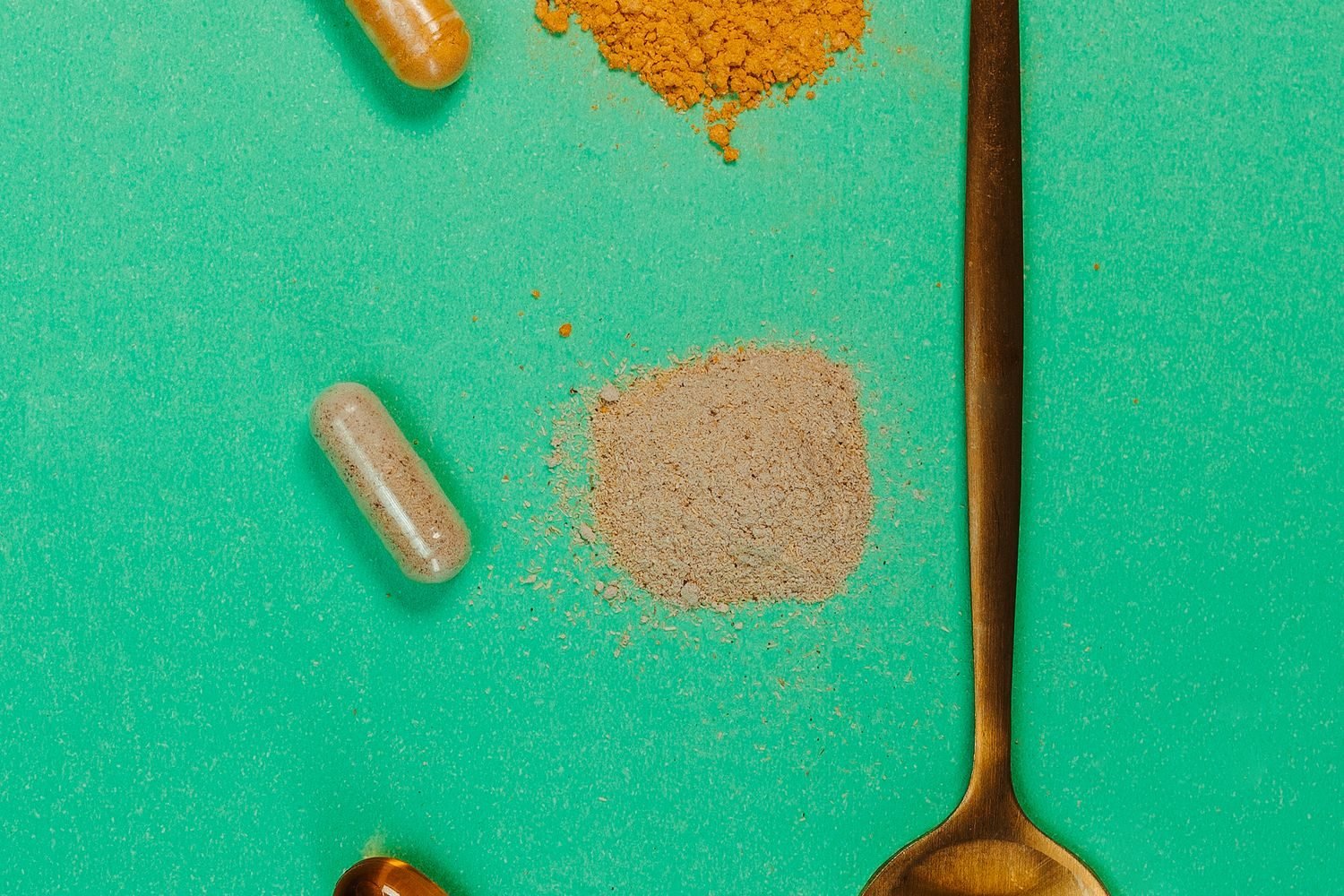Ashwagandha root, shatavari root, and Ayurvedic herbal capsules arranged next to a bowl of whole foods