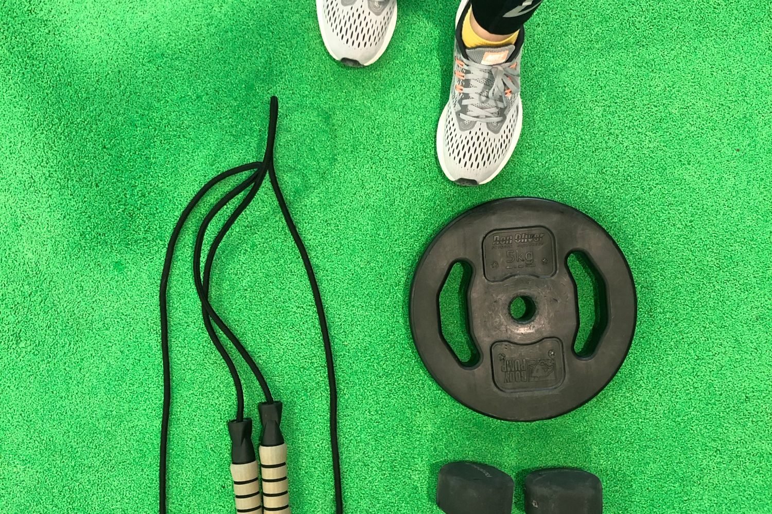 Jump rope, a weight plate, and dumbbells laid out on the floor for a beginner HIIT workout at home