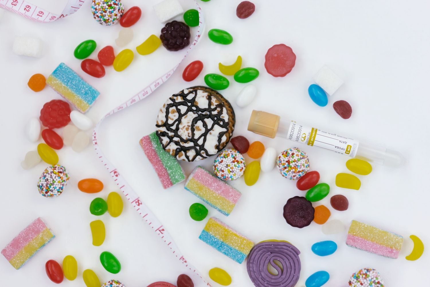 Assortment of high-added-sugar foods and drinks including soda, pastries, and candy next to a nutrition label