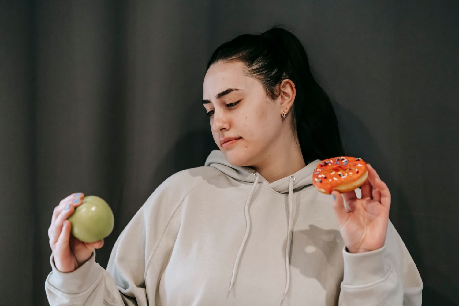 Woman choosing fresh fruit over sugary snacks in her kitchen as a strategy to manage sugar cravings