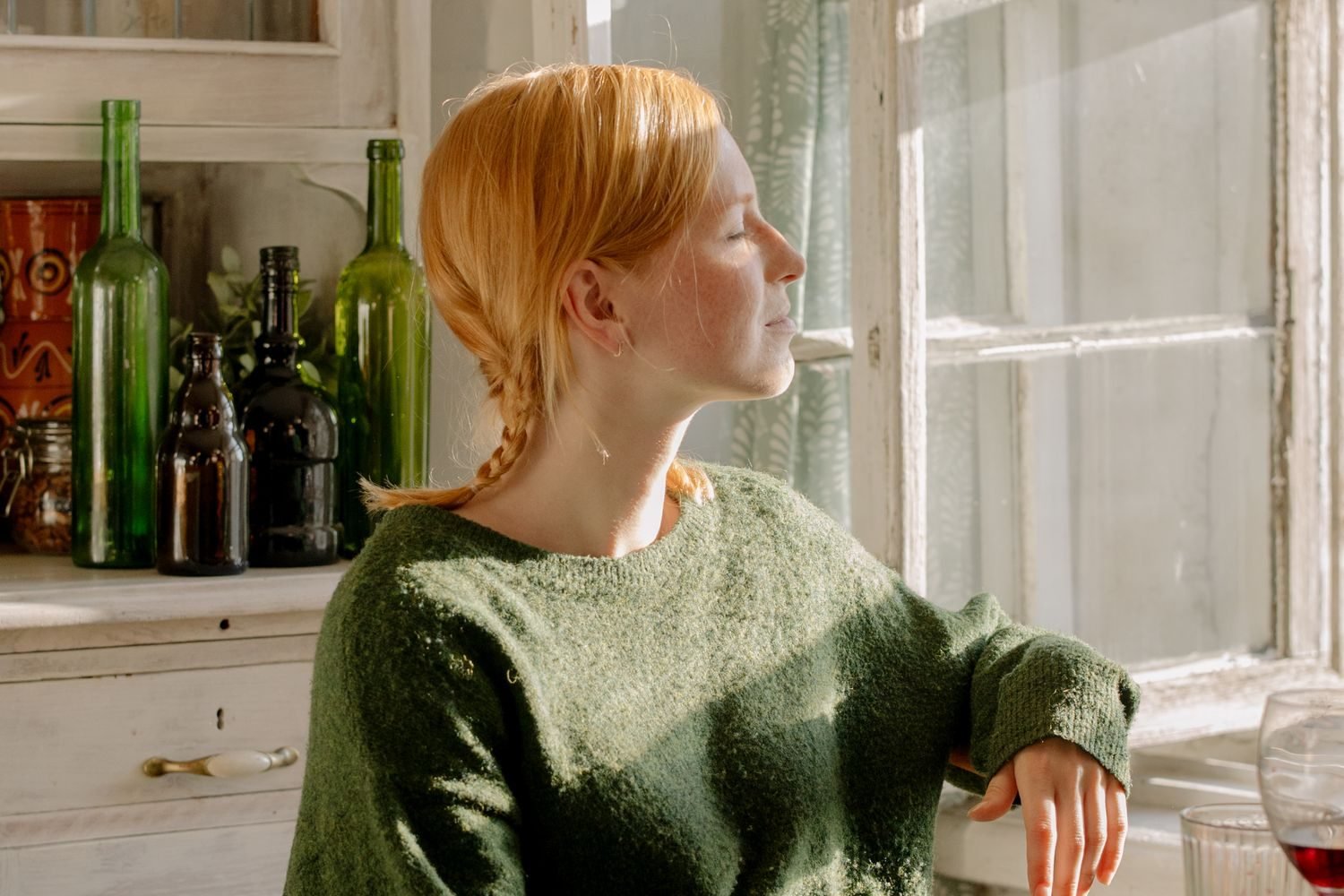 Person sitting calmly at a kitchen table with a glass of water, reflecting rather than restricting after eating