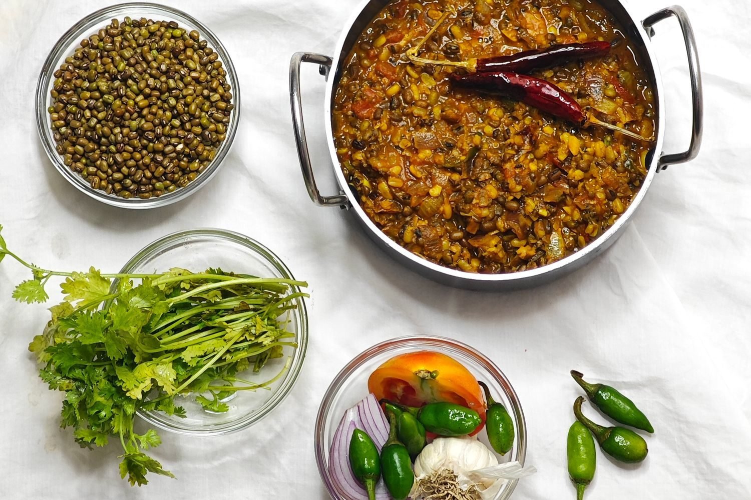 Bowls of dal, eggs, soya chunks, and sprouted moong on a kitchen table representing affordable Indian protein sources