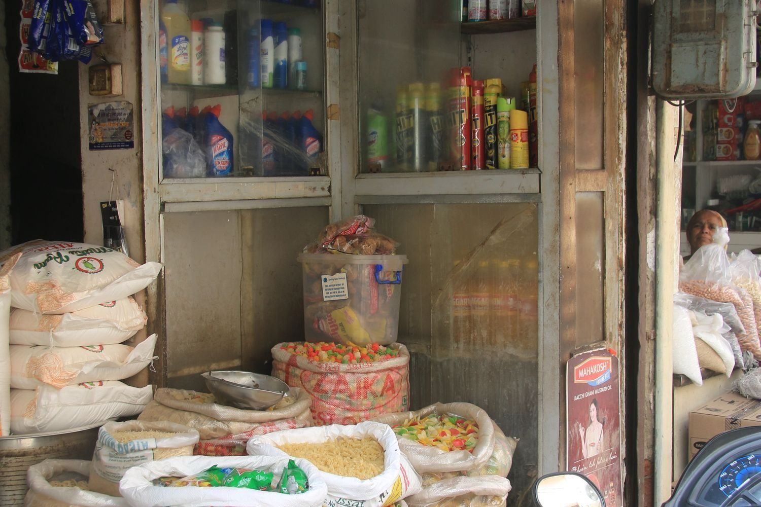 Large sacks of rice, wheat atta, and dal at an Indian kirana store showing bulk grocery buying