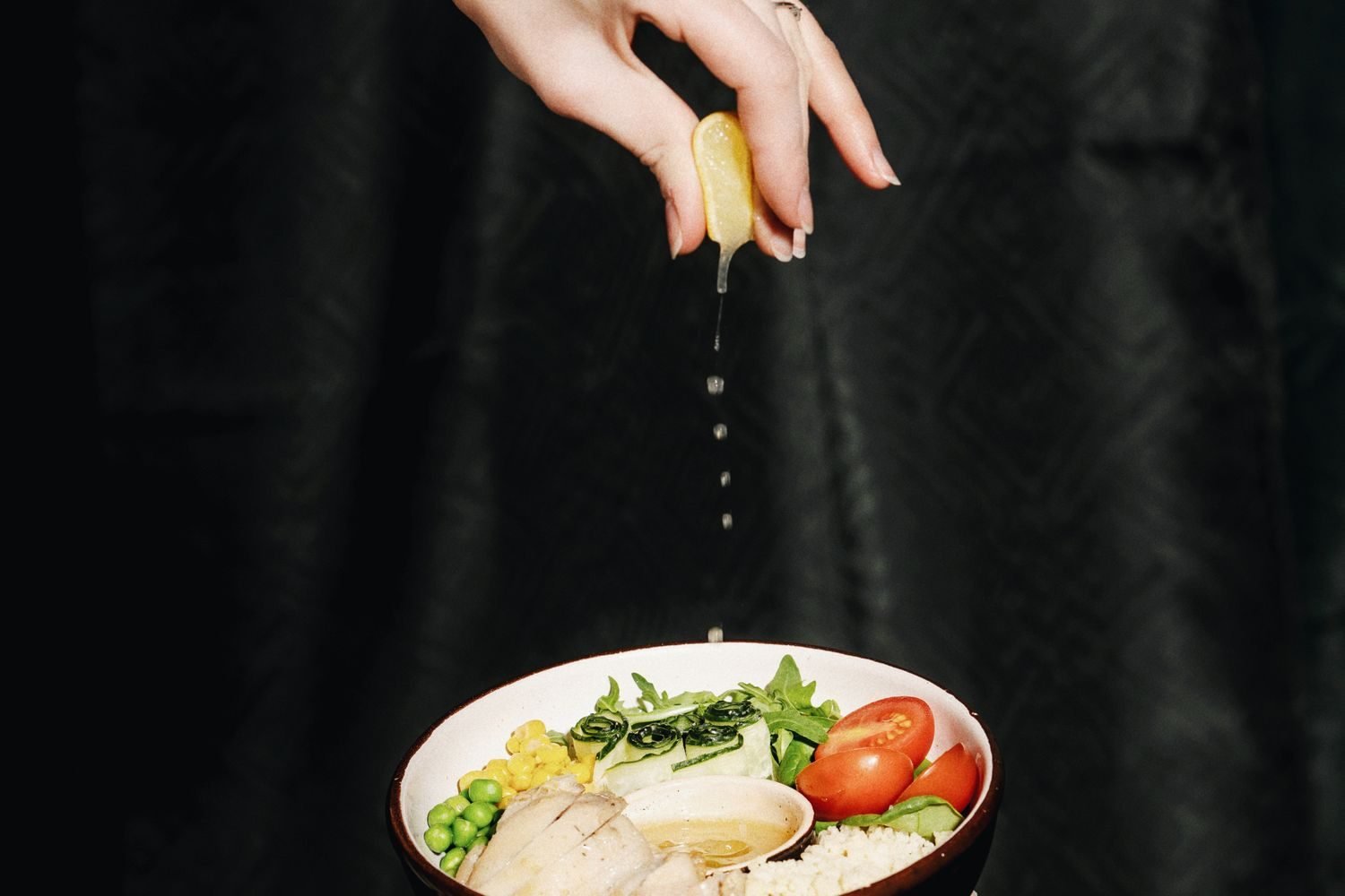 Lemon being squeezed over a bowl of dal to lower the glycemic response of the meal